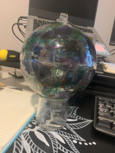 Glass ornament with tree inside sitting on desk